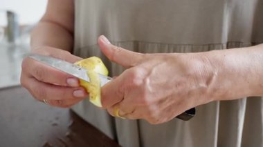 Mutfak patatesi hazırlama, ev yapımı patates soyma, patates soyma, patates soyma sahnesi, patates püresi hazırlama, doğal ışıklandırma ve buruşuk eller. Ağır çekim. 4k