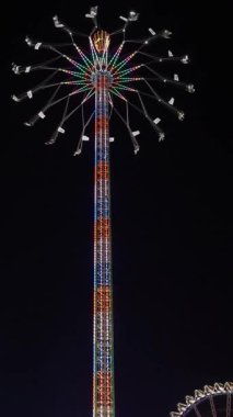 Parlak parlayan teller ve dönen gölgeliklerin yer aldığı gökyüzü yüksekliğinde bir eğlence gezisi. Gece aydınlatmalı salıncak, dönen kanopi ile, 4k