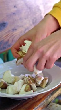 Taze mantarlar beyaz tabakta, ahşap masada, görünür sarı kollu, ev yemeği.