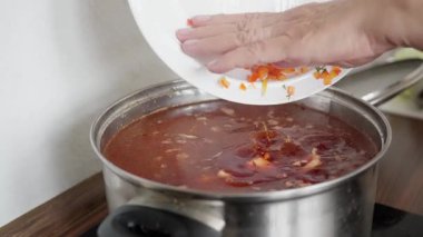 Sebze pişirme çorbası, hazırlanmış malzemeler ve ev yapımı sebze çorbası, doğranmış sebzeler sıcak domates suyuna karıştırıldı. Buhar paslanmaz kabın içinde yükseliyor.