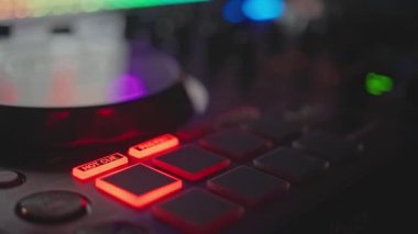 Stüdyoda parlayan kırmızı düğmeler ve koşu tekerleği derinliği sığ alan iç karartıcı düşük ışık dokunmatik modern elektronik müzik ekipmanı üreticisi iş akışını kontrol ediyor.