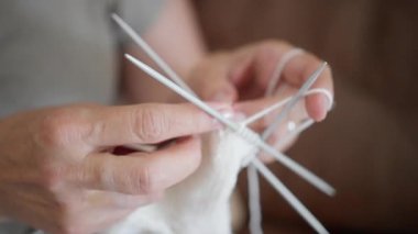 Beyaz çorap ören, beyaz çorap ören, çift uçlu iğneler ve yumuşak yün iplik, sıcak oturma odasındaki ışıkta dikişlerle ayak parmağı şekillendiren yaşlı zanaatkar, yavaş terapötik ritim, el yapımı...
