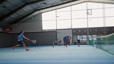 kapalı alanda tenis servisi, erkek rakip kapalı alanda yoğun servis tekniği sergiliyor, dinamik tenisçi güçlü kapalı servis uygulaması sırasında başınızın üstünde raket uzatıyor