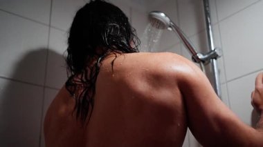 Duşun altındaki rahat adam, banyodaki sıcak suyun tadını çıkaran adam, tuvaletteki yumuşak su akıntısı adamı sakinleştiren adam, sıcak banyodaki dinlendirici duşla gevşeyen adam.