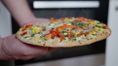 Elde taze pişmiş sebzeli pizza, mısır, kırmızı biber, soğan, maydanoz ve erimiş peynirli pizzayla kaplanmış sıcak ve ince dilimlenmiş pizza.