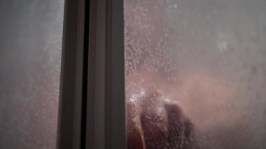 Duştaki kaslı beyaz adam, omuzlarını ve göğsünü su damlacıklarıyla kapatan, ıslak uzun saçlı, banyolu, el kameralı, duşlu, duşlu, duşlu, duşlu, duşlu, duşlu, dumanlı cam panelli, bastırılmış sinematik ışıklandırma, hassas. 4k