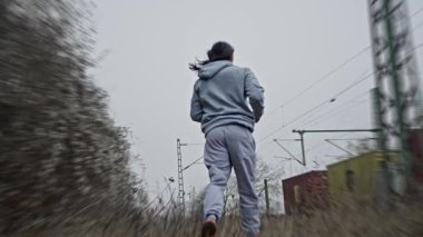 Kapüşonlu Adam Manzarayı Geçiyor, Kapüşonlu Bireyler Demiryolu boyunca Uzaktan Skyline 'a doğru koşuyor, Kapüşonlu Adam Giderek Giderek Giderek Giderek Azalan Horizon' a doğru Çimlerin Üzerinde İlerliyor,