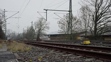 Bulutlu Gök Altındaki Boş Eğri Raylar, Elektrik Kateneri ve Polonyalılar Çakıltaşı Kütlesi, Rutubetli Platform ve Uzak İstasyon Binası, Sönük Tonları Endüstriyel Sınır Bilim ve Sakinleştirici Yokluğu