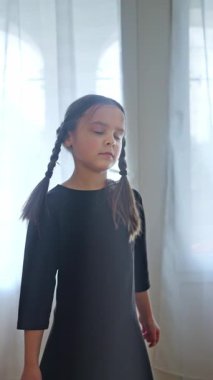 Neşeli örgülü neşeli bir çocuk güneşli bir odada neşeyle dans eder, saf masumiyet ve mutluluğu yakalar. Yavaş çekim