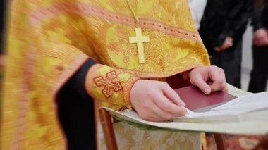 Rahibin elleri açık dua kitabında, işlemeli altın yelek kolunda görünür, Yavaş Sayfa Çevirimi ve Yumuşak Odaklı Kilise İçi, Edebiyat Dönemi Saygıdeğer Atmosfer, Parmaklar Sakinleştirilmiş .4k