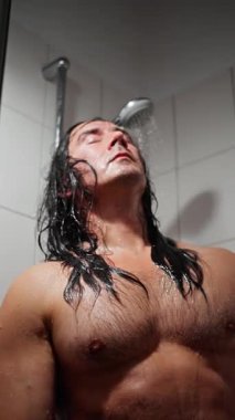 Duşun Altında Üstsüz Beyaz Adam, Omuzların Üzerinde Uzun Islak Saçlar, Düşük Açı Banyolar, Kaslı Göğüsteki Su Damlacıkları, İç Gözler Kapalı, Buharlı Atmosfer,