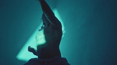 Dövüş sanatları gösterisi. Studio Silhouette Serene Focus 'ta Disiplinli Dövüş Sanatçısı Yakalıyor. Erkek Uygulayıcı Barışçıl Teal Üçgeni Parıltısı Altında Kasıtlı Dövüş Sanatları Hareketi Uyguladı