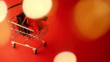 Hediye paketi alışveriş arabasında. Noel indirimi. Uzayı kopyala Maytap bulanık. Kırmızı arka plan. Yeni Yıl Kutlaması