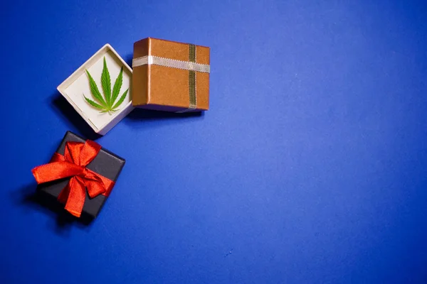 Noel 'i kutlayalım. Kenevir yaprağı. Marihuana yeni yıl afişi. Hediye kutuları. Mavi arka plan. Boşluğu kopyala