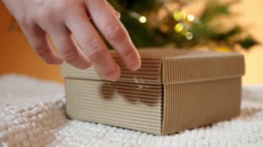 Ellerini kapat ve hediyeyi aç. Noel ışıkları. Kahverengi kutu. Tatil mucizesi 