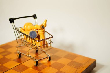 Satranç taşları alışveriş arabasında yatıyordu. İnternetten oyun al. İş stratejisi. Beyaz arkaplanda satranç tahtası 