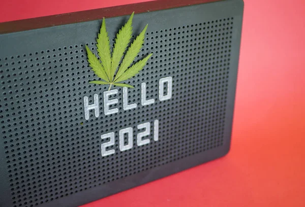 Merhaba 2021. Mesaj. Kenevir yaprağı. Kırmızı arka plan. Yeni yıl kutlaması. Esrar sembolü 