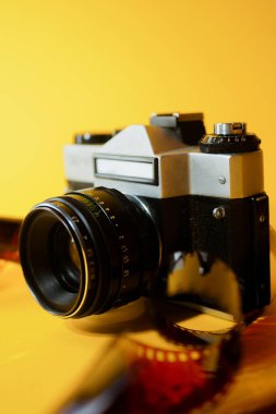 35 mm 'lik filmli analog kamera. Sarı arka plan. Fotoğraf hobisi. Dikey yönelim 