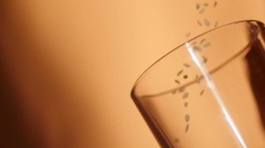 Close up sesame grains falling in the glass. Slow motion video