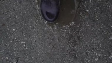 Üst manzara lastik çizmelerle yürüyor. Yağmurlu bir hava. Kirli ve yolda su var.