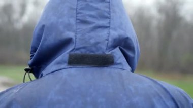 Yağmurluklu bir adam dışarıda yürüyor. Yağmurlu hava aktivitesi