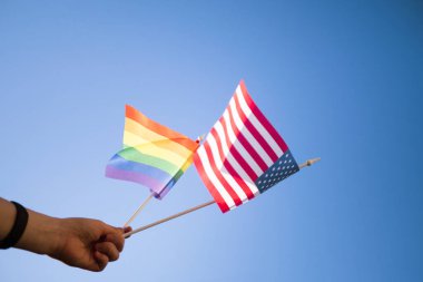 El ele tutuşan ABD ve LGBT bayrakları. Gurur ayı konsepti. Gay geçit töreni. Aynı cinsiyet hakları 
