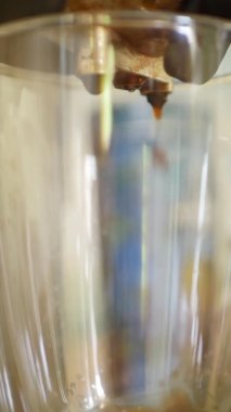 Şeffaf fincana dökülen koyu kahveyi kapat. 4k dikey video. Kahve makinesiyle espresso yapıyorum. 