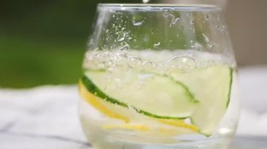 Masada limonlu ve salatalıklı bir bardak su. Taze limonata dolduruyorum. Yaz ev yapımı kokteyller. 4k video