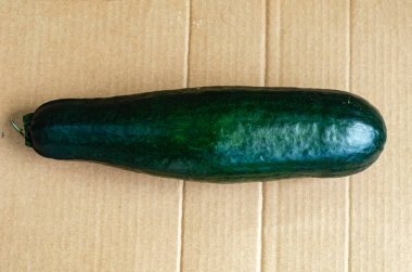 Olgun, uzun yeşil bir kabak kahverengi bir karton kağıdın üzerinde yatıyor..