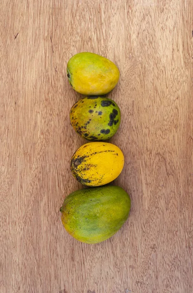 緑の肌 ジュリー 斑点のあるロビン 黄色の熟した一般的なマンゴーのラインがボード表面にあります ストックフォト