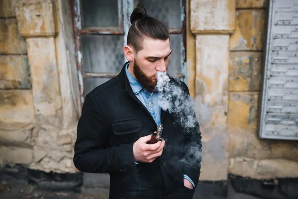 Homem com barba fumar cigarro eletrônico ao ar livre Fotografia De Stock