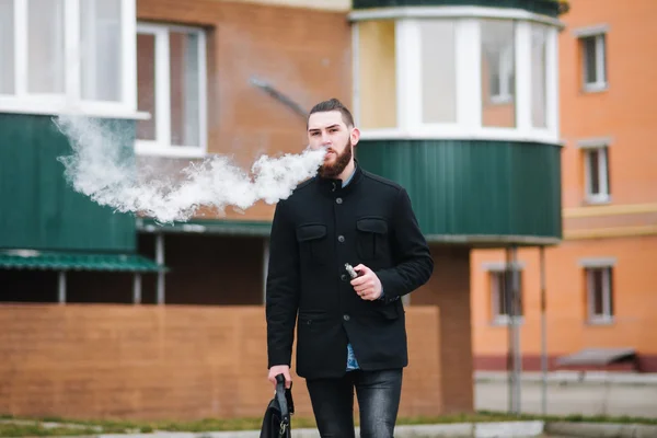 Homem com barba fumar cigarro eletrônico ao ar livre Fotografia De Stock