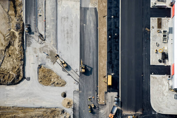 Industrial Construction Site Shot from Above. Aerial View of an excavator, Bulldozers and Trucks working on a construction Area.