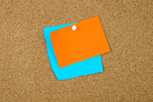 Notas en blanco de papel turquesa y naranja fijadas en el tablero de corcho — Foto de Stock