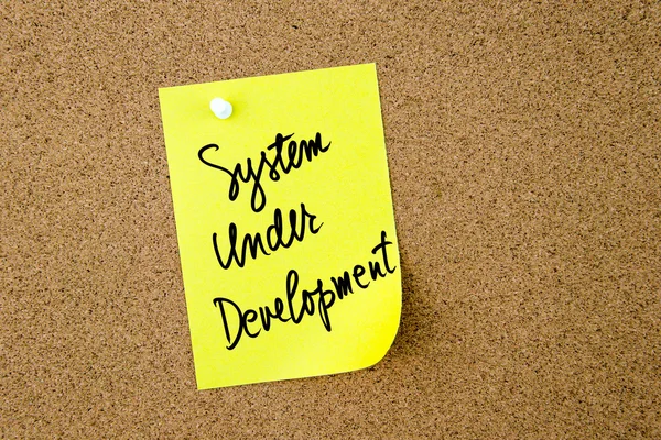 Sistema en desarrollo escrito en papel amarillo nota — Foto de Stock