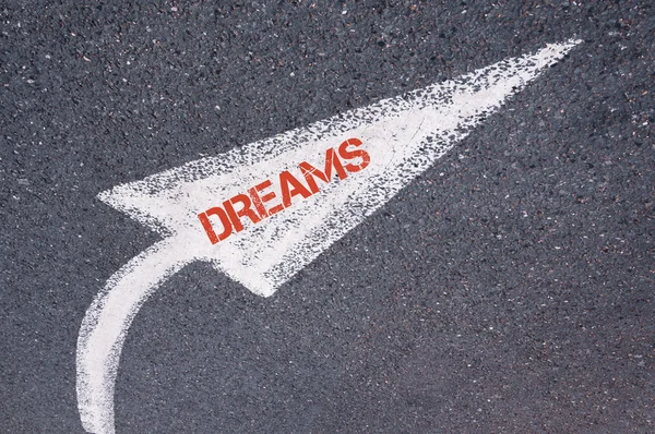 Directional white painted arrow with word DREAMS over road surface — Stock Photo, Image