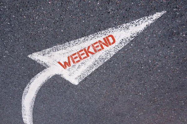 Напрямна біла пофарбована стрілка зі словом WEEKEND над поверхнею дороги — стокове фото