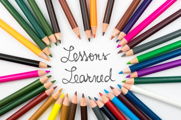 Colouring pencils in circle arrangement with message Lessons Learned — Stock Photo, Image