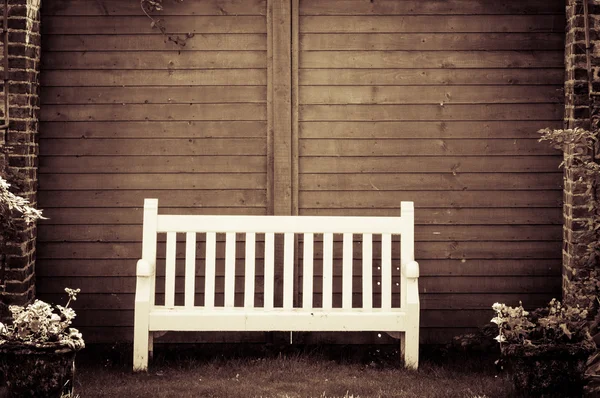 Banc de jardin en bois blanc dans le jardin anglais, filtre de couleur rétro appliqué — Photo