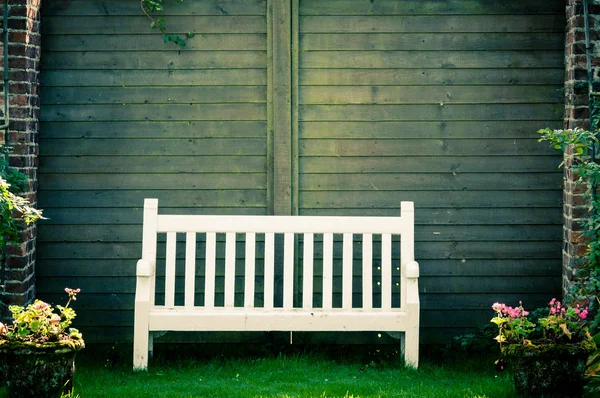 Banco de jardín de madera blanca en jardín inglés, filtro de color retro aplicado — Foto de Stock