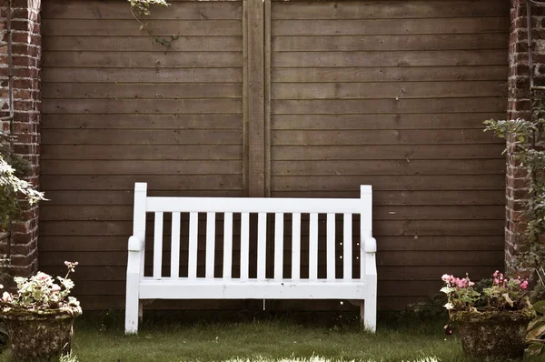 White Wooden garden bench in English garden, retro color filter applied — Stock Photo, Image