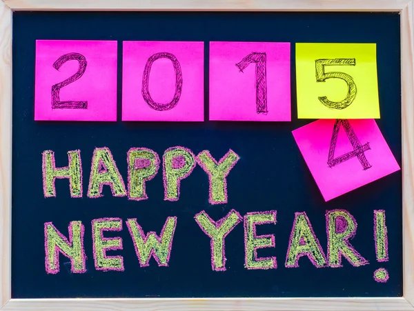 Feliz Año Nuevo 2015 mensaje escrito a mano en pizarra, números indicados en notas post-it, 2015 sustitución de 2014, concepto de celebración de la oficina corporativa — Foto de Stock