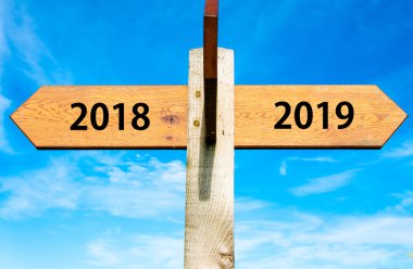 Açık mavi gökyüzü, yıl 2018 ve 2019 işaretler, Happy New Year kavramsal görüntü üzerinde iki zıt oklarla ahşap tabela