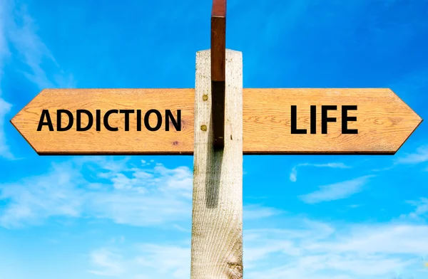 Wooden signpost with two opposite arrows over clear blue sky, Addiction and Life signs, Choice conceptual image — Stock Photo, Image