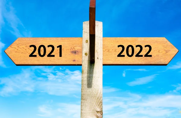 Wooden signpost with two opposite arrows over clear blue sky, year 2021 and 2022 signs, Happy New Year conceptual image — Stock Photo, Image