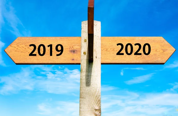 Wooden signpost with two opposite arrows over clear blue sky, year 2019 and 2020 signs, Happy New Year conceptual image — Stock Photo, Image