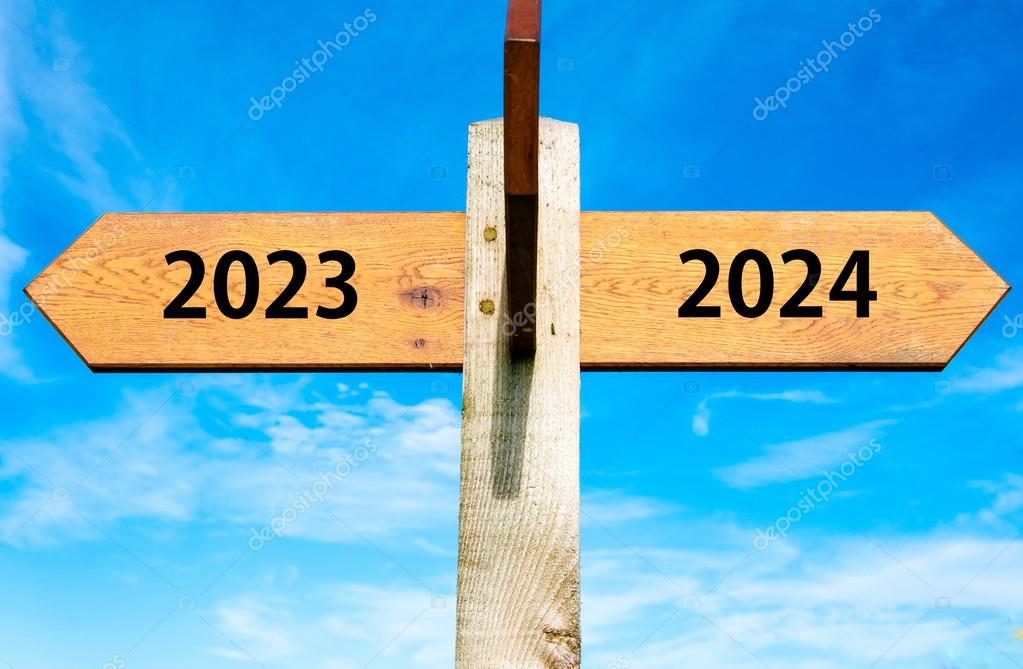 Wooden signpost with two opposite arrows over clear blue sky, year 2023