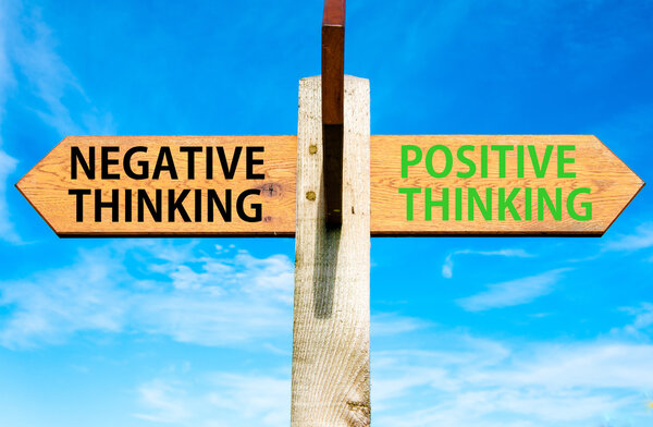 Wooden signpost with two opposite arrows over clear blue sky, Negative versus Positive Thinking messages, Mindset conceptual image