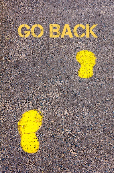 Yellow footsteps on sidewalk towards Go Back message — Stock Photo, Image