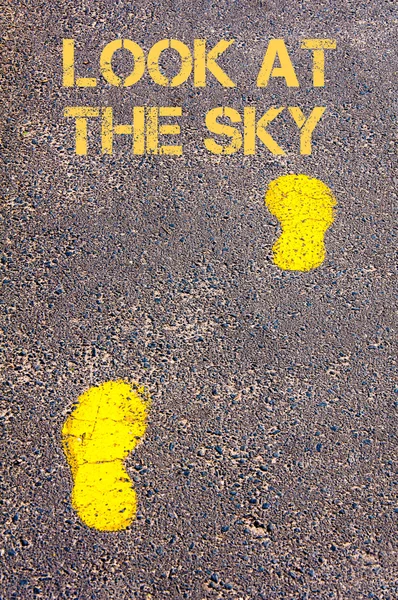 Yellow footsteps on sidewalk towards Look at the sky message — Stock Photo, Image